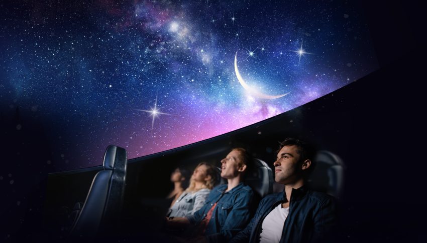 Row of people looking up at the night sky and universe in a planetarium