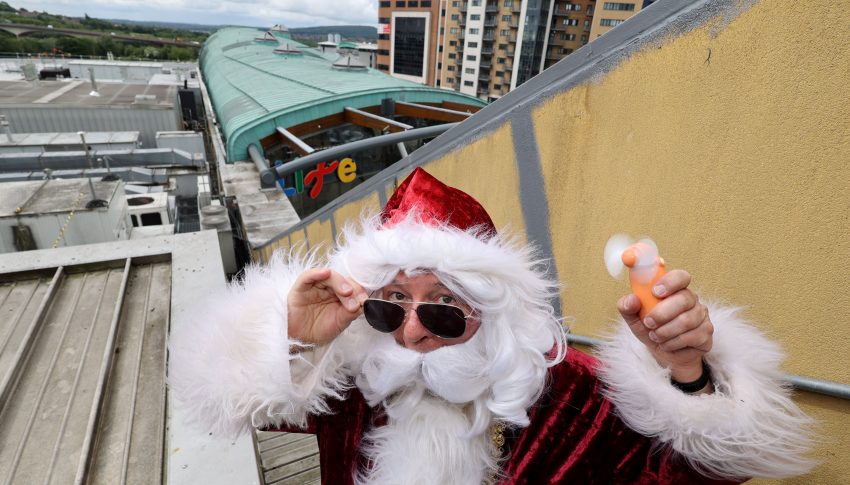 Santa holding an electric hand-held fan on top of Centre for Life's roof