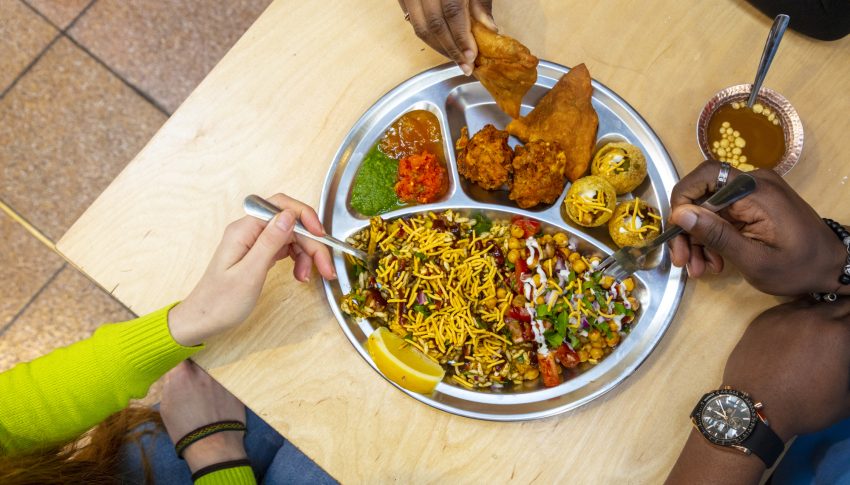 Three people tucking into one dish of food.