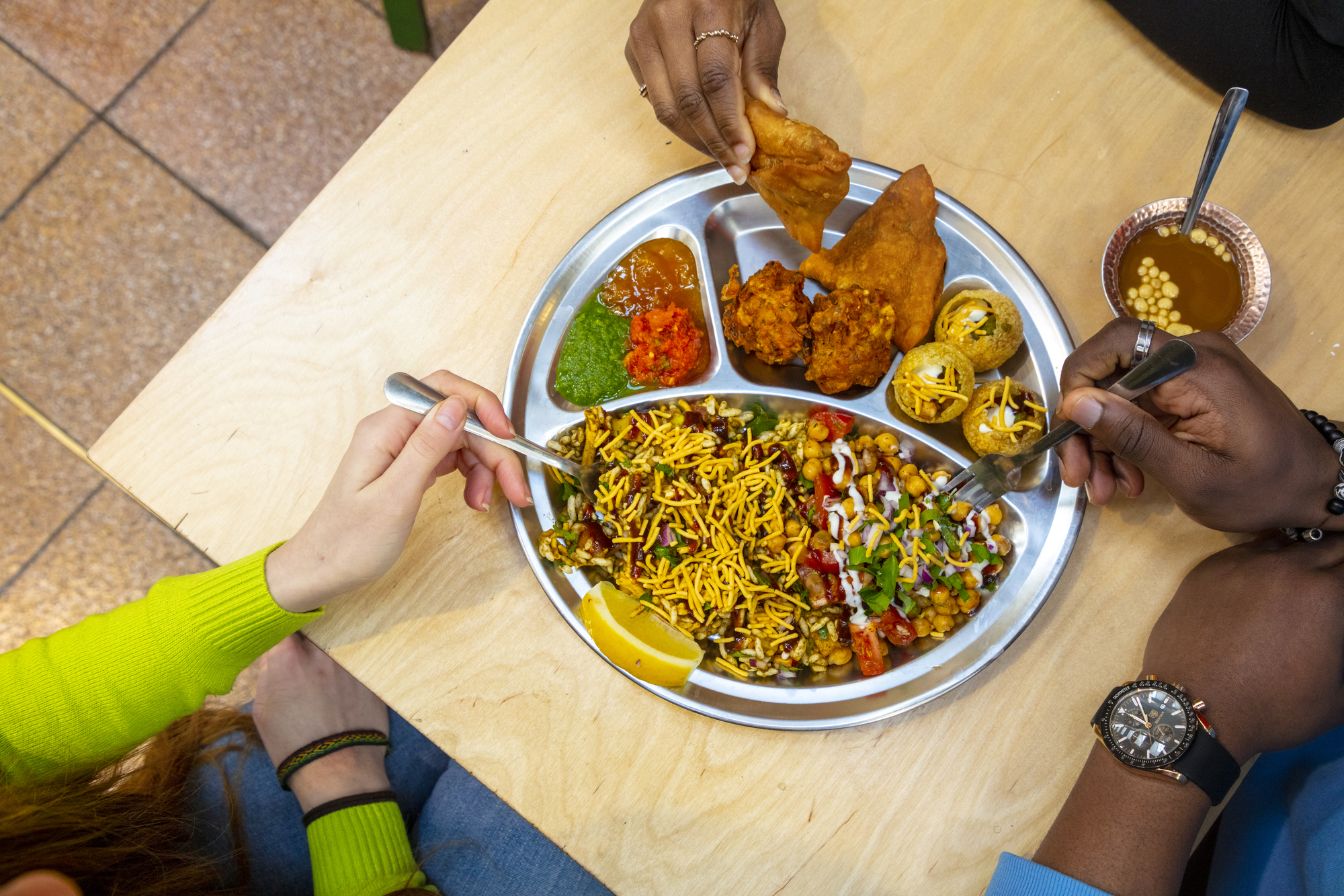 Three people tucking into one dish of food.