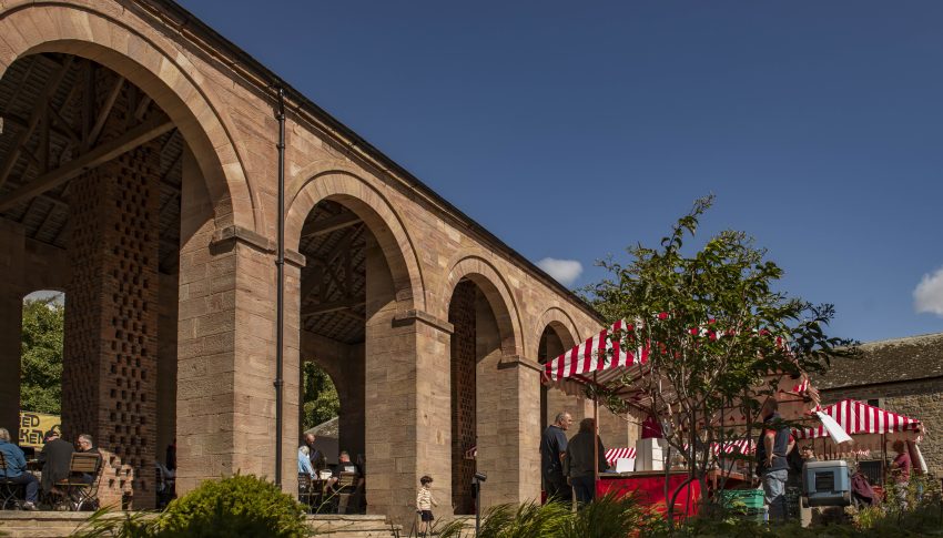 Red and white market stalls outside the arches of the Raby barn.