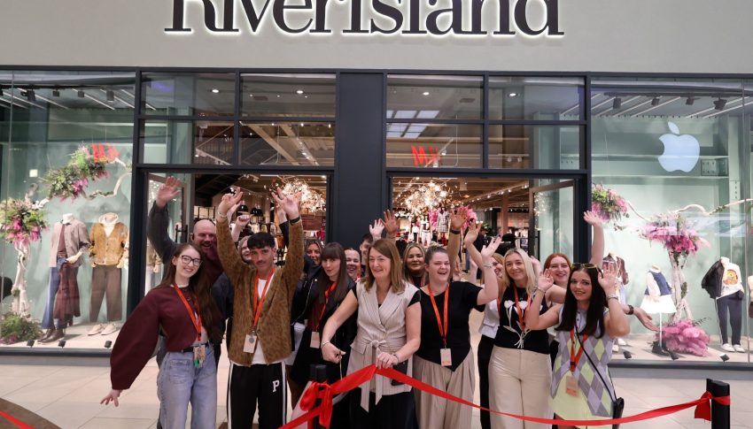 Group of people outside of River Island store cutting a red ribbon.