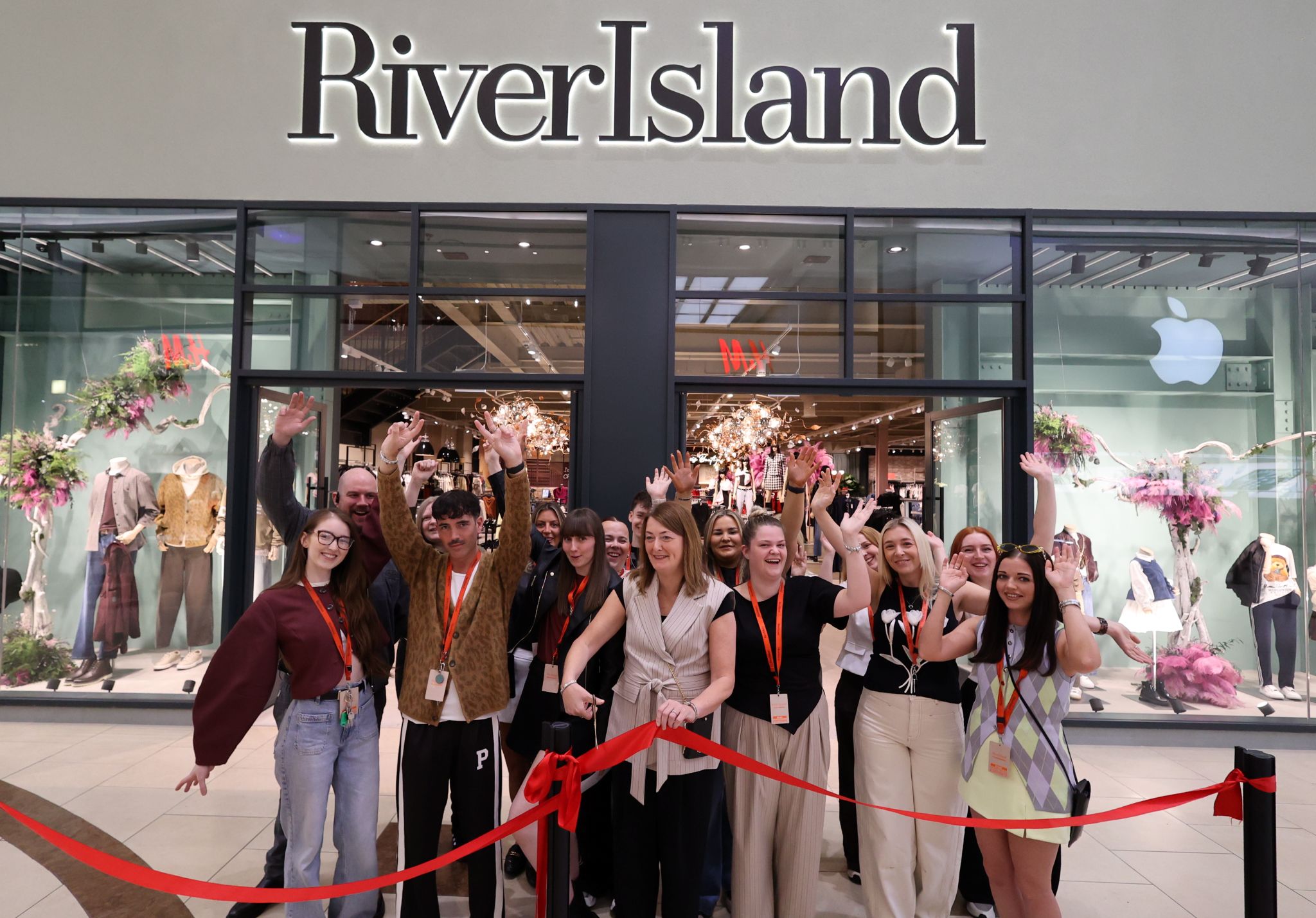 Group of people outside of River Island store cutting a red ribbon.