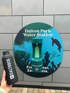Hydration station on a wall with a reusable water bottle in the camera person's hand in the foreground.