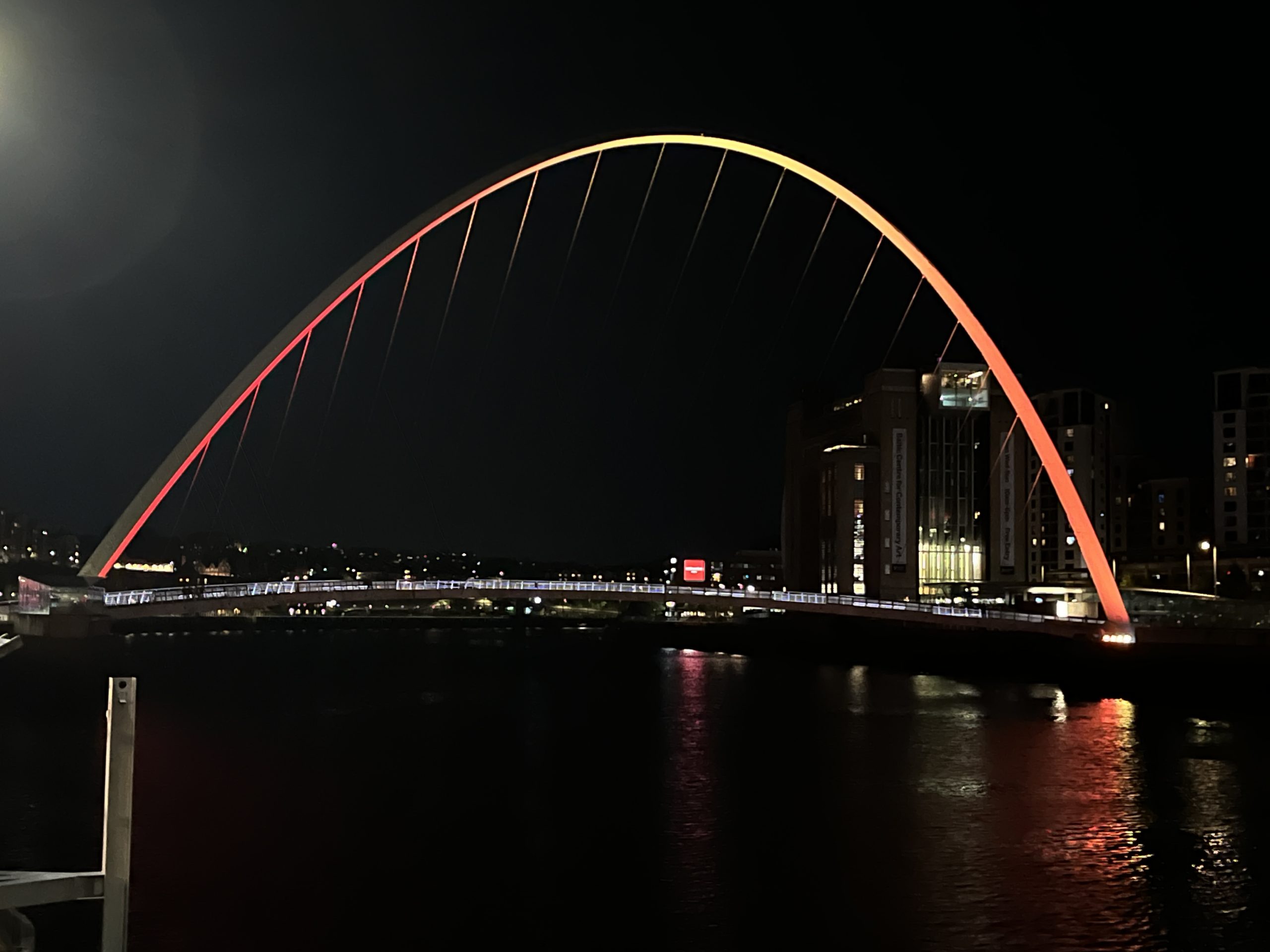Millennium Bridge over the River Tyne lit up in red and orange.