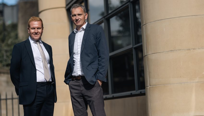 Alex and Damien standing together outside of Ward Hadaway offices smiling to camera.