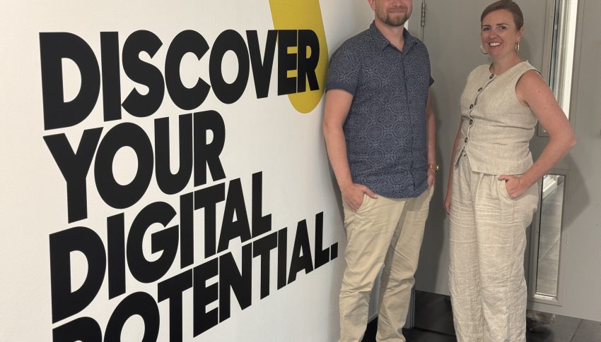 Two people stood next to wall with Gateshead College branding.