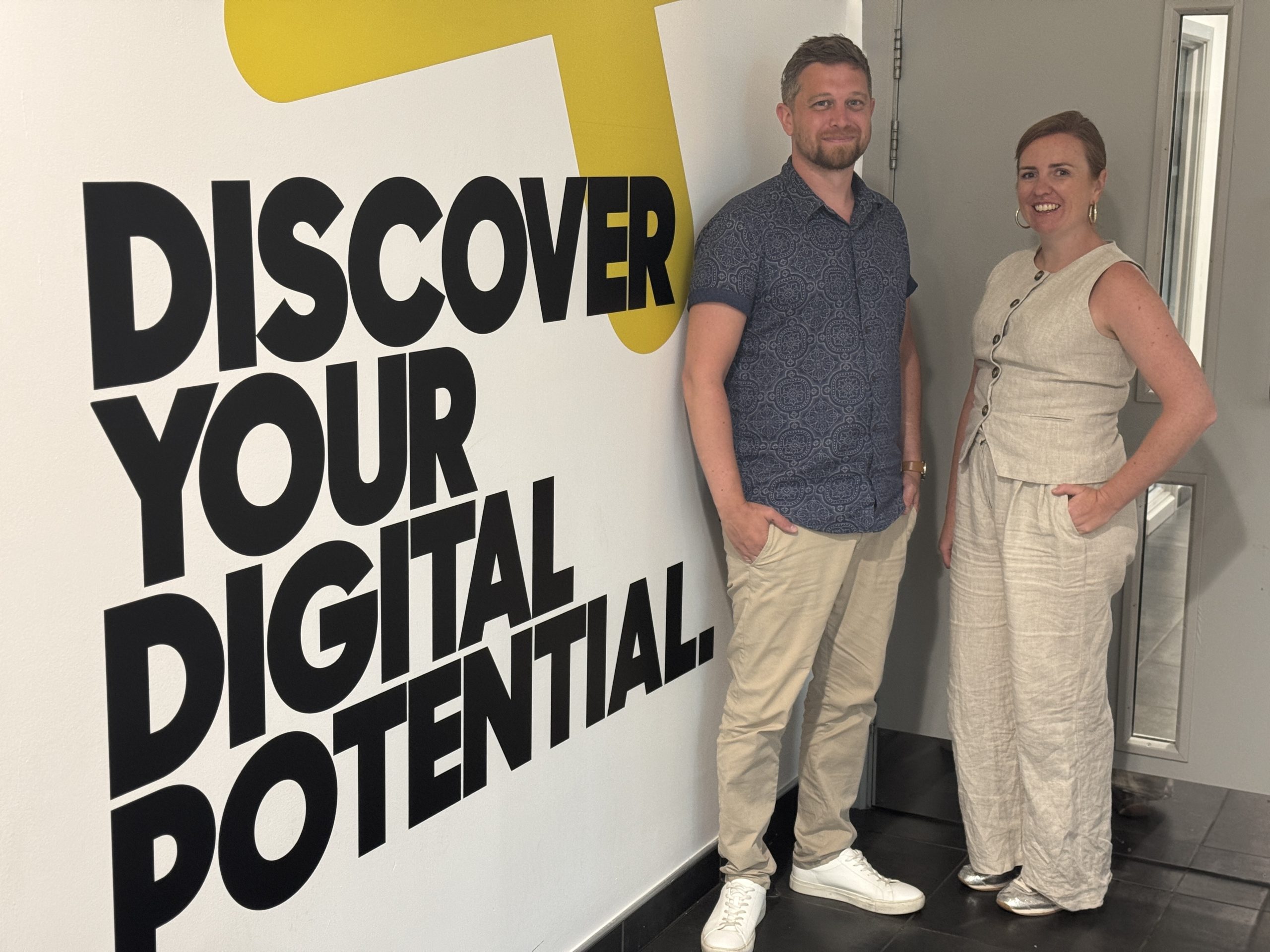 Two people stood next to wall with Gateshead College branding.