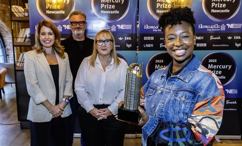 Kim, Gavin, Karen and YolanDa posing with the Mercury Prize award in front of branded backdrop.