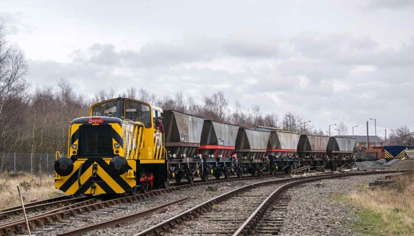 Train with yellow and black chevrons on the front running through some tracks.