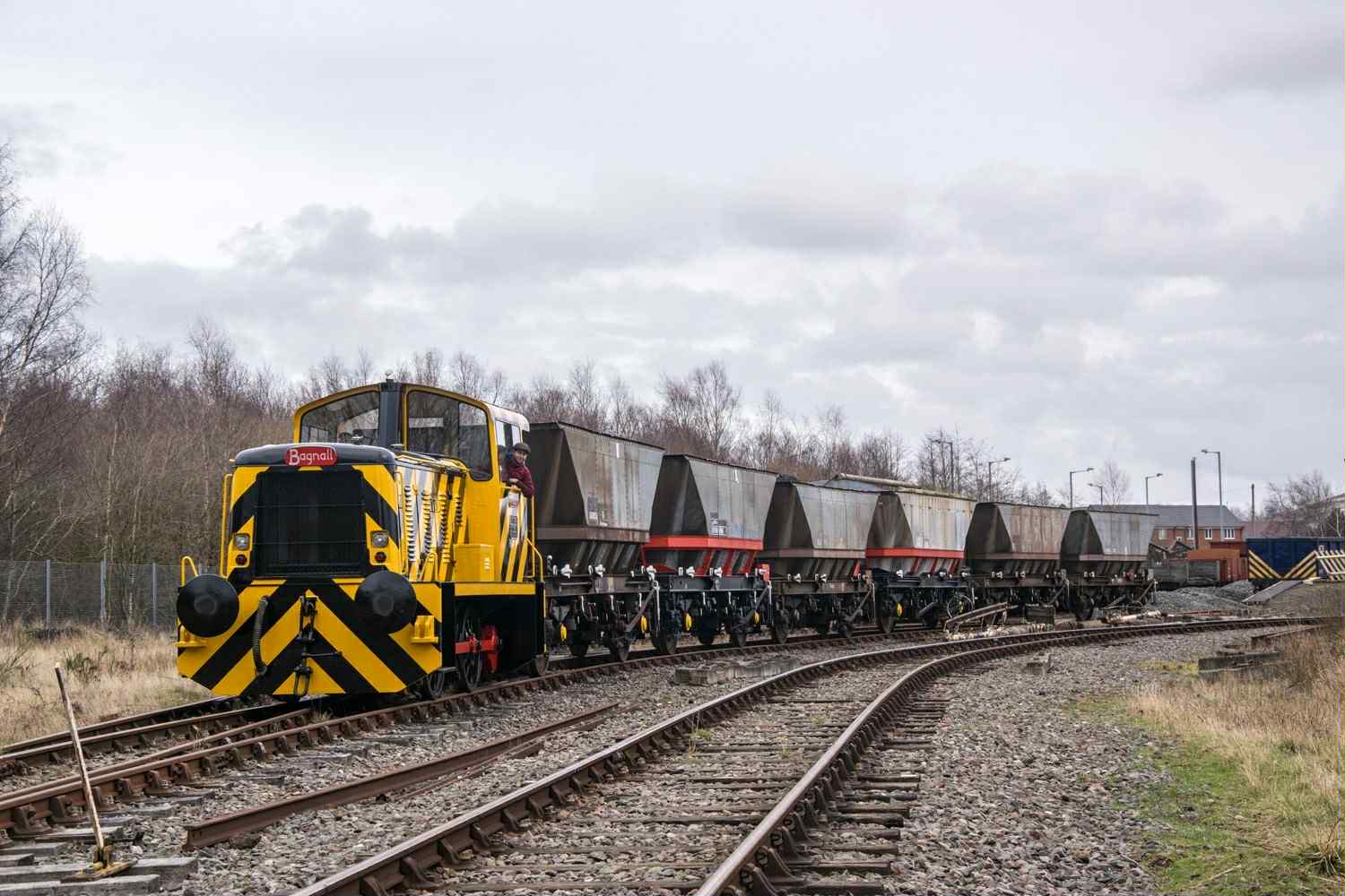 Train with yellow and black chevrons on the front running through some tracks.