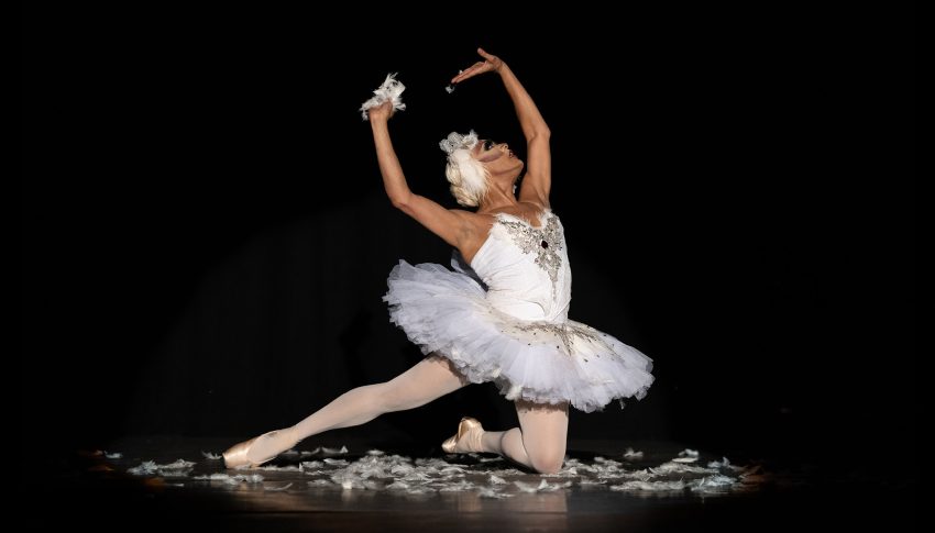 Ballerina performing dramatically on a dark stage