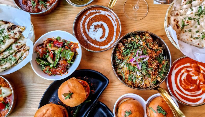 Lots of small plates with food on a wooden table.