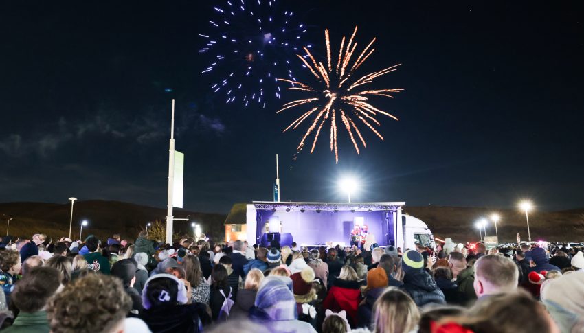 Firwework display taking place with a crowd of people looking on from below.