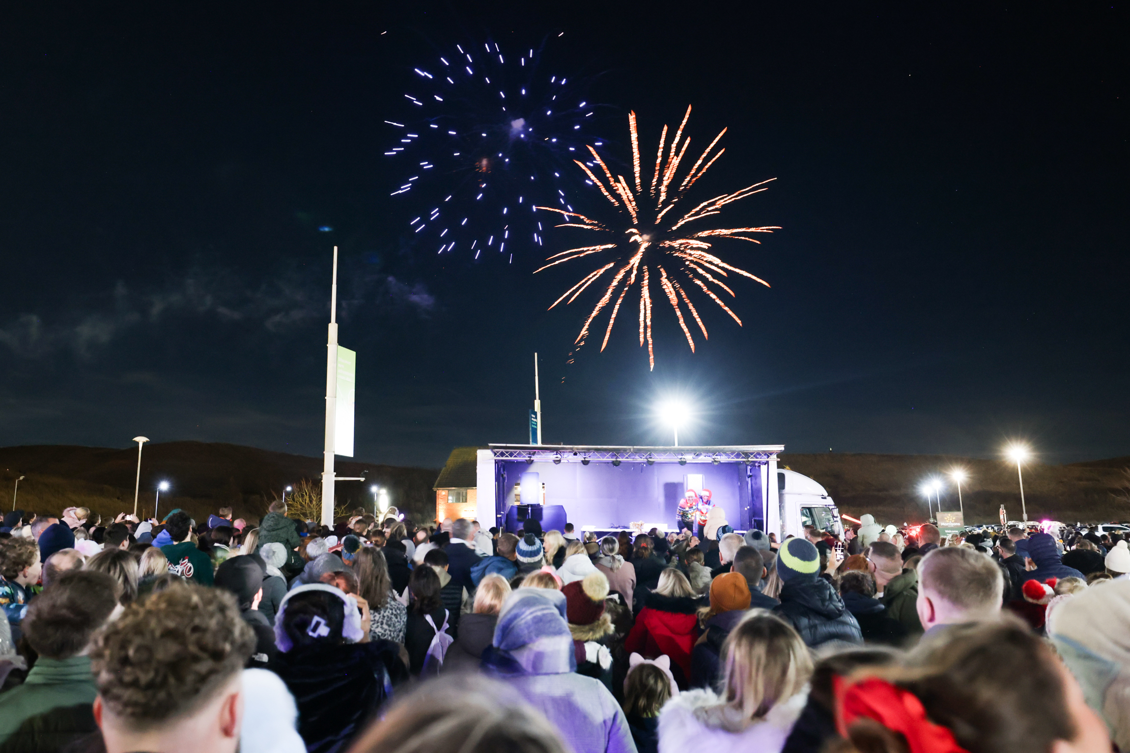 Firwework display taking place with a crowd of people looking on from below.