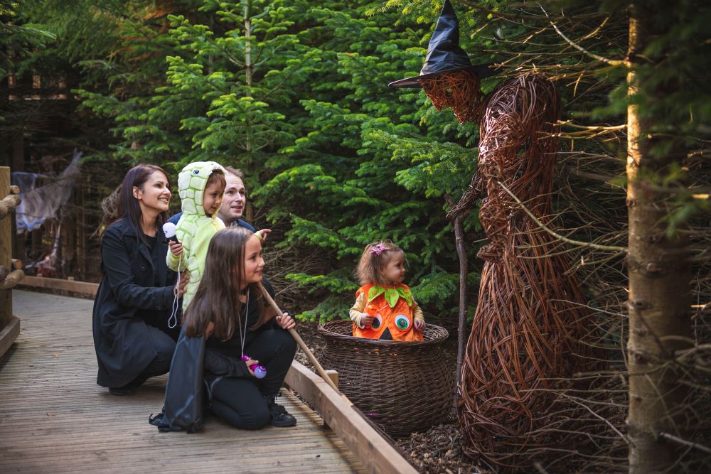 Group of children and parents walking through Halloween-decorated nature.