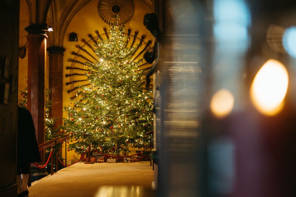 A large Christmas tree with gifts underneath at the end of a corridor in Raby Castle.