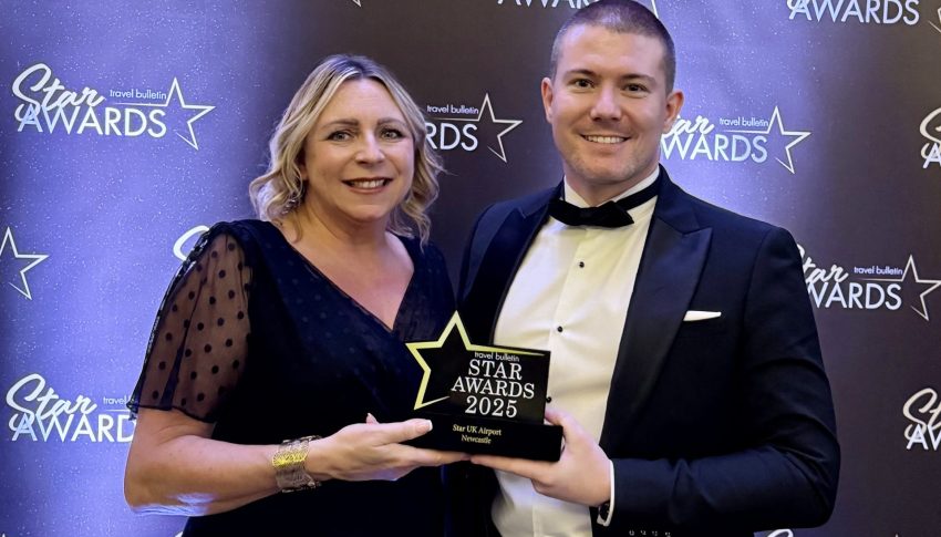 Laura and Chris holding up their award in front of the awards banner in black-tie attire.