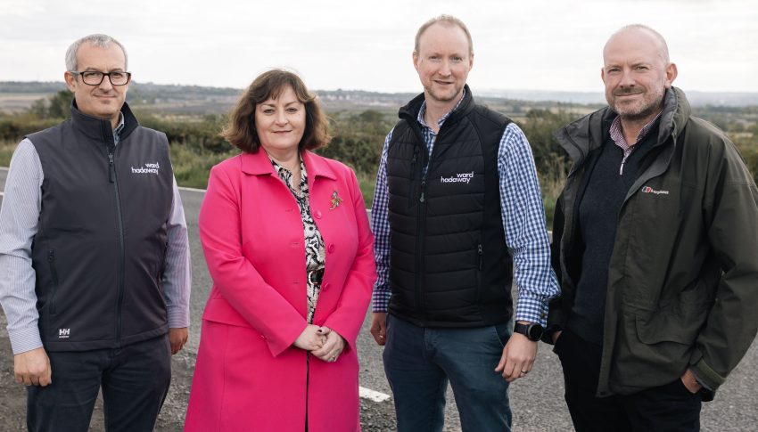 Group of four people stood near a field wearing warm clothing.
