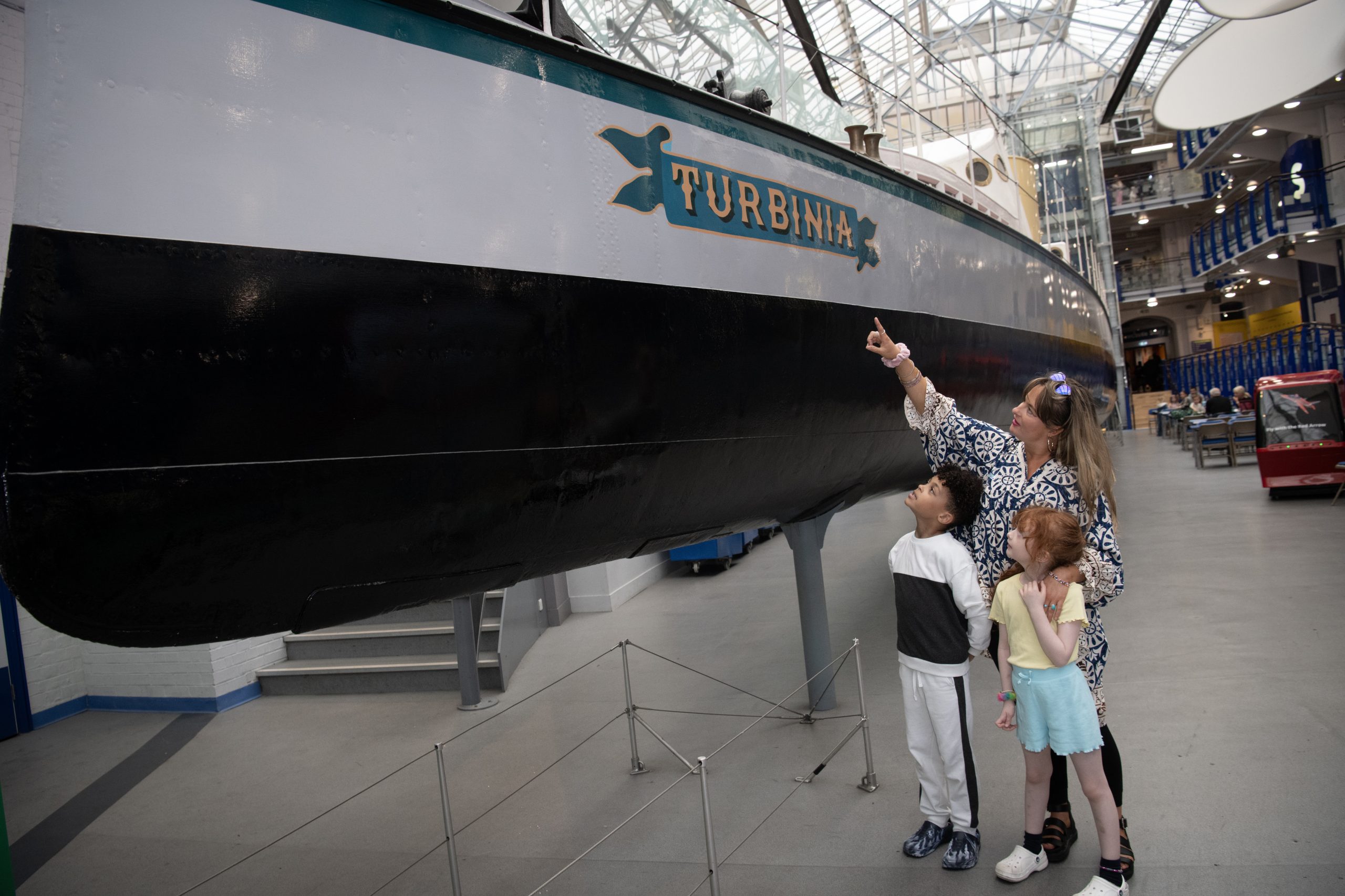 Parent and children looking up at large ship inside the Discovery Museum.