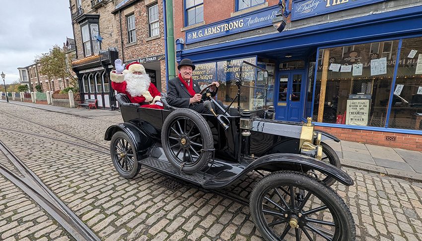 Santa Claus and Victorian -style driver in an old-fashioned car on the street in Beamish Museum.