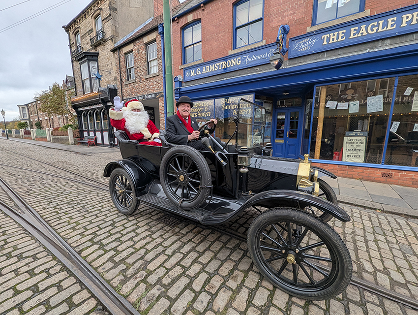 Santa Claus and Victorian -style driver in an old-fashioned car on the street in Beamish Museum.