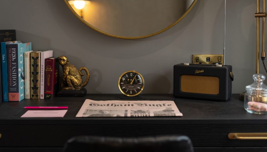 Desk space in Gotham Hotel room, books, a clocl and vintage radio are all on the desk.
