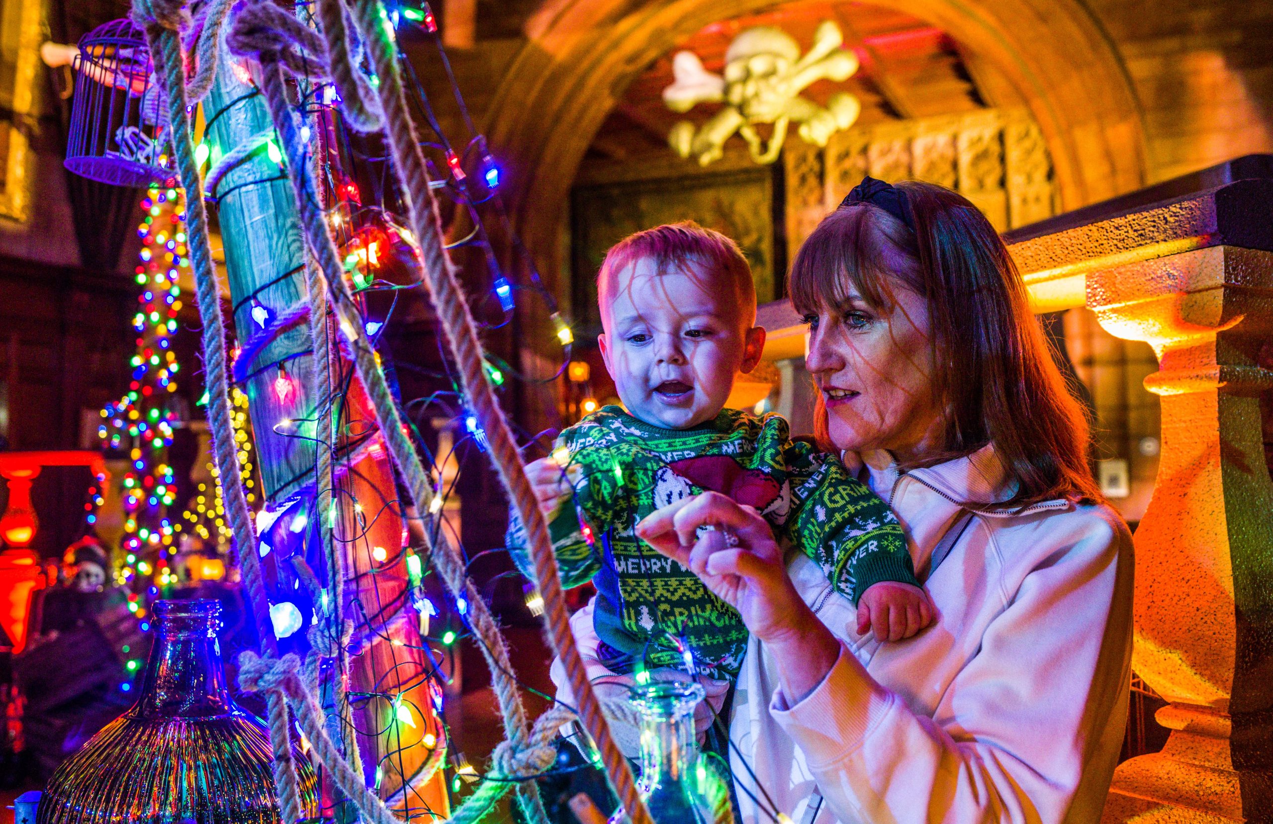 Family exploring the Trasured Tales experience at Bamburgh Castle. THey are in a colourful room full of twinkling lights.