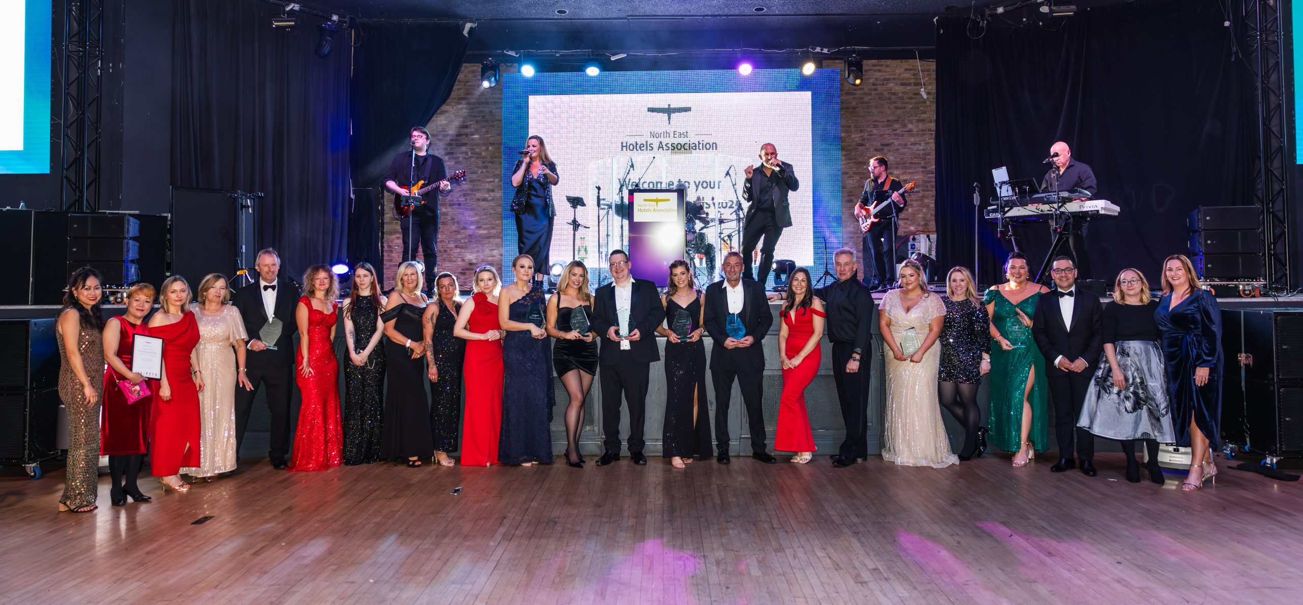 Winners from North East Hotels Association Awards celebrating together on stage.