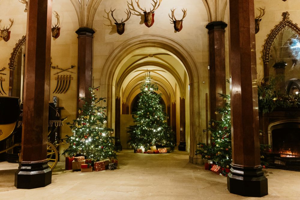 Raby Castle hallway with Christmas trees lining the sides.
