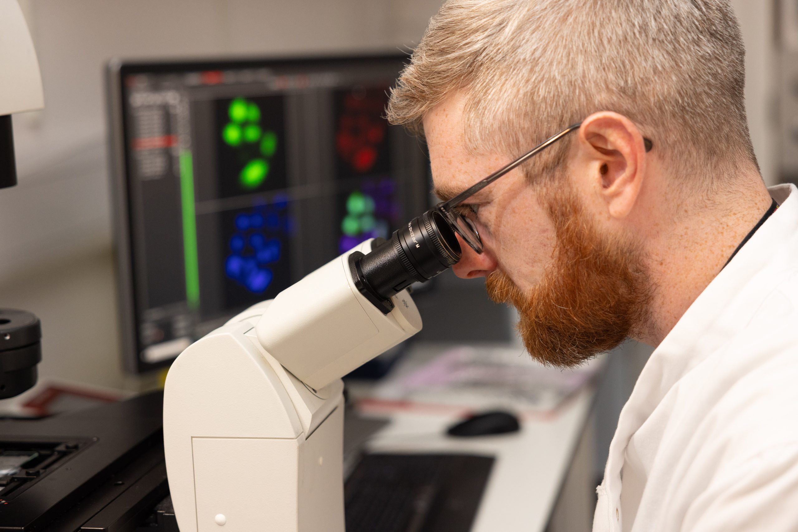 Technician examining cells through a microscope
