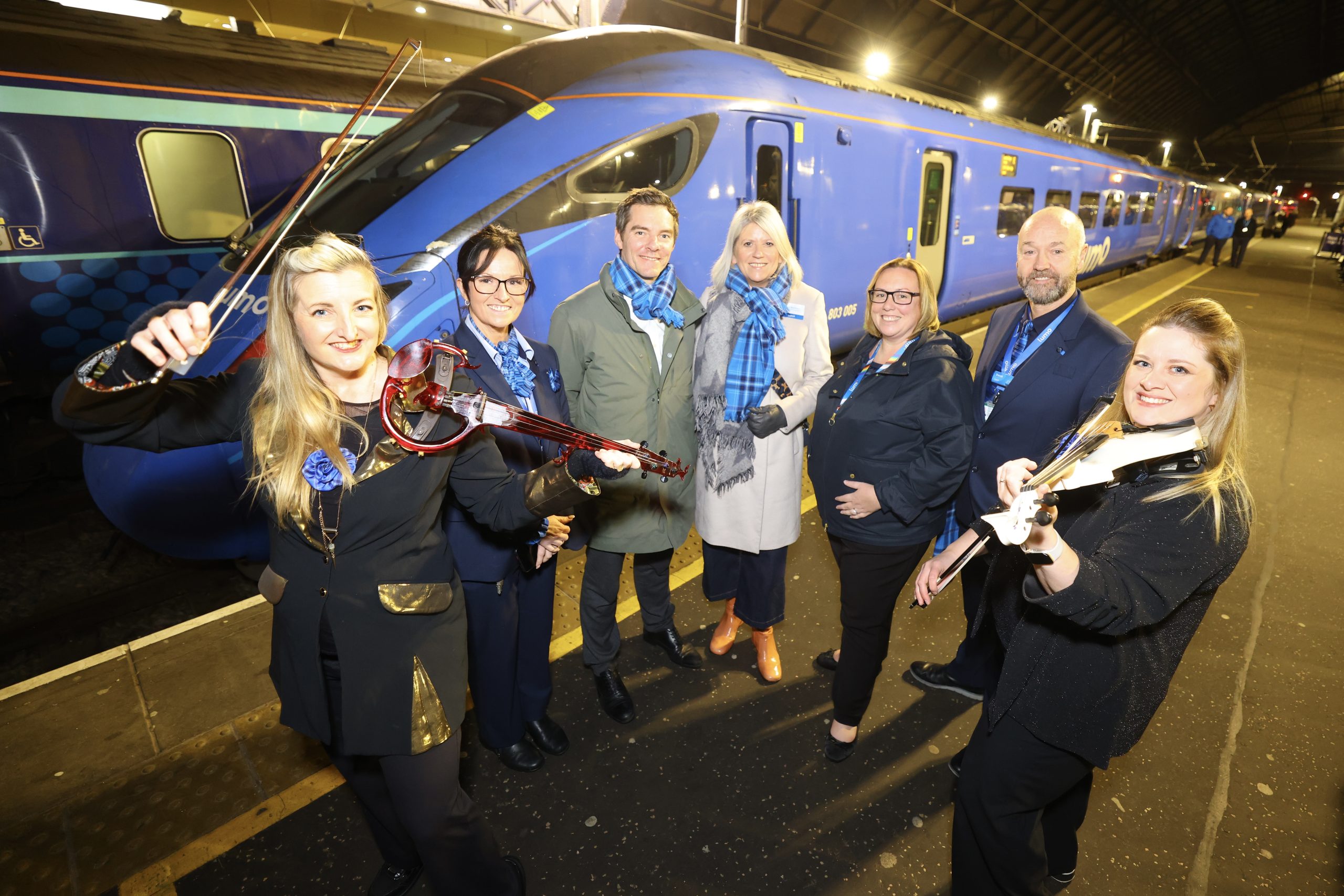 Lumo team standing in front of a blue train.