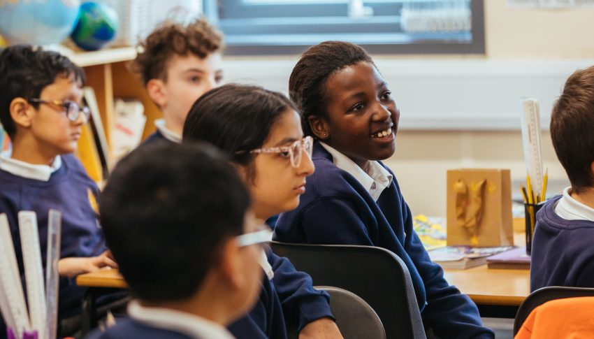 Group of primary school pupils sat in classroom smiling