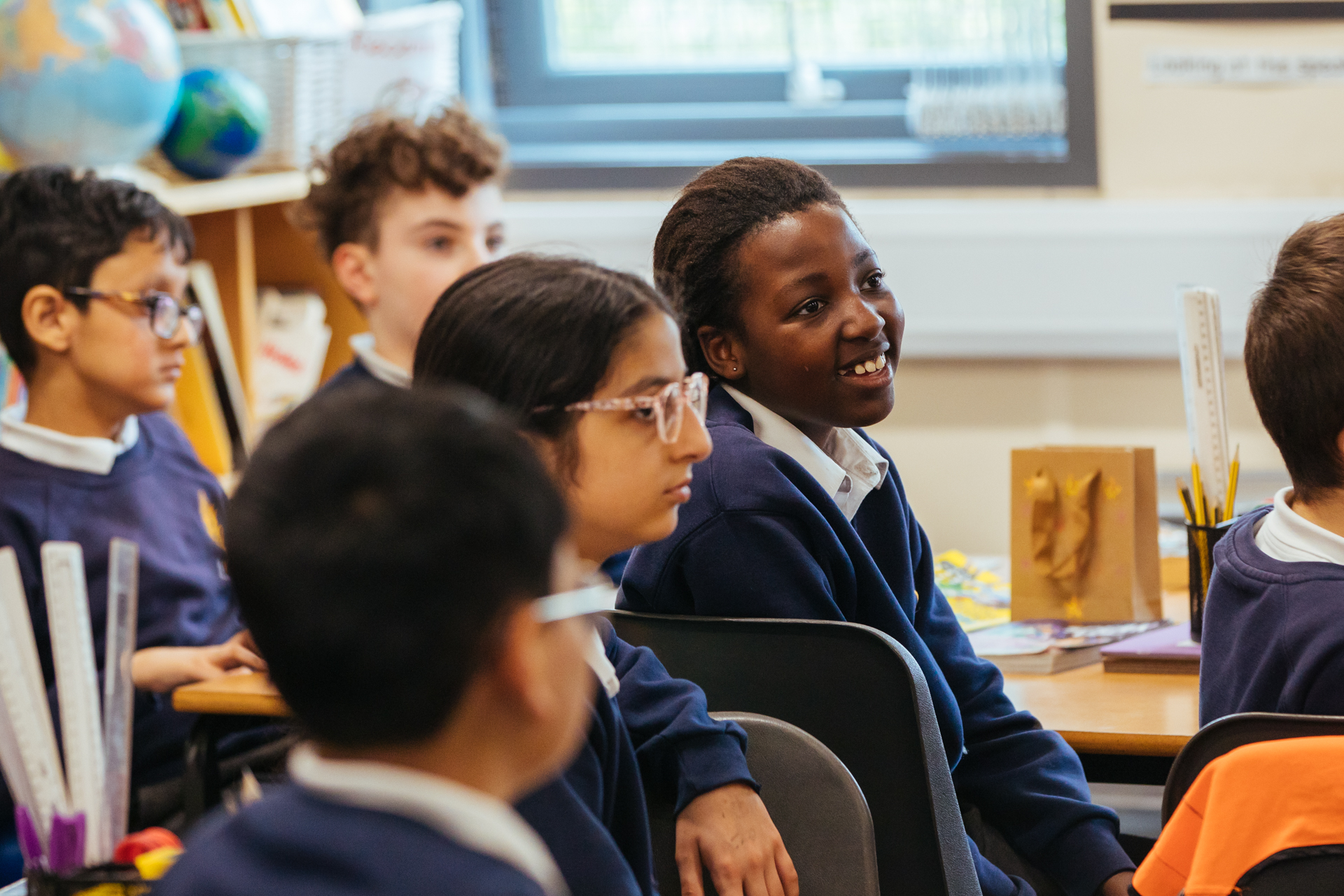 Group of primary school pupils sat in classroom smiling