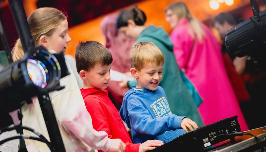 Children using a sound board at a theatre.