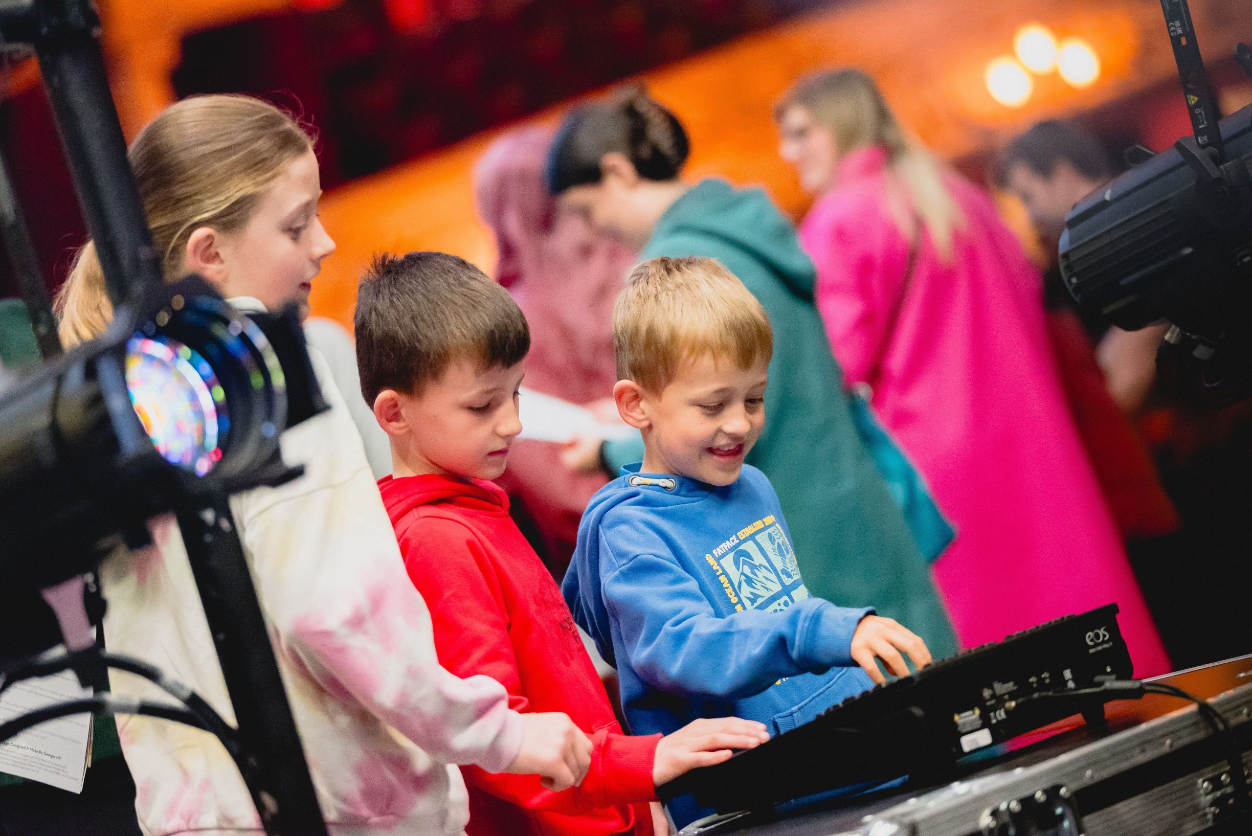 Children using a sound board at a theatre.