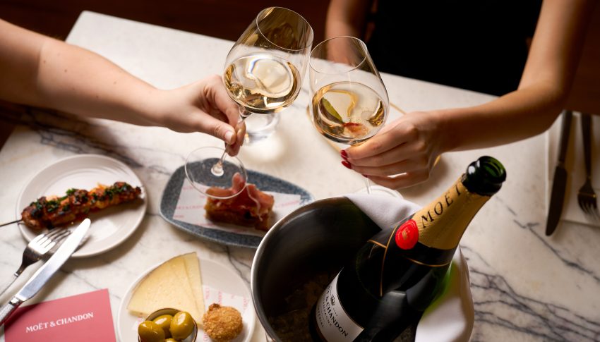 Two wine glasses and champagne bottle being cheered.