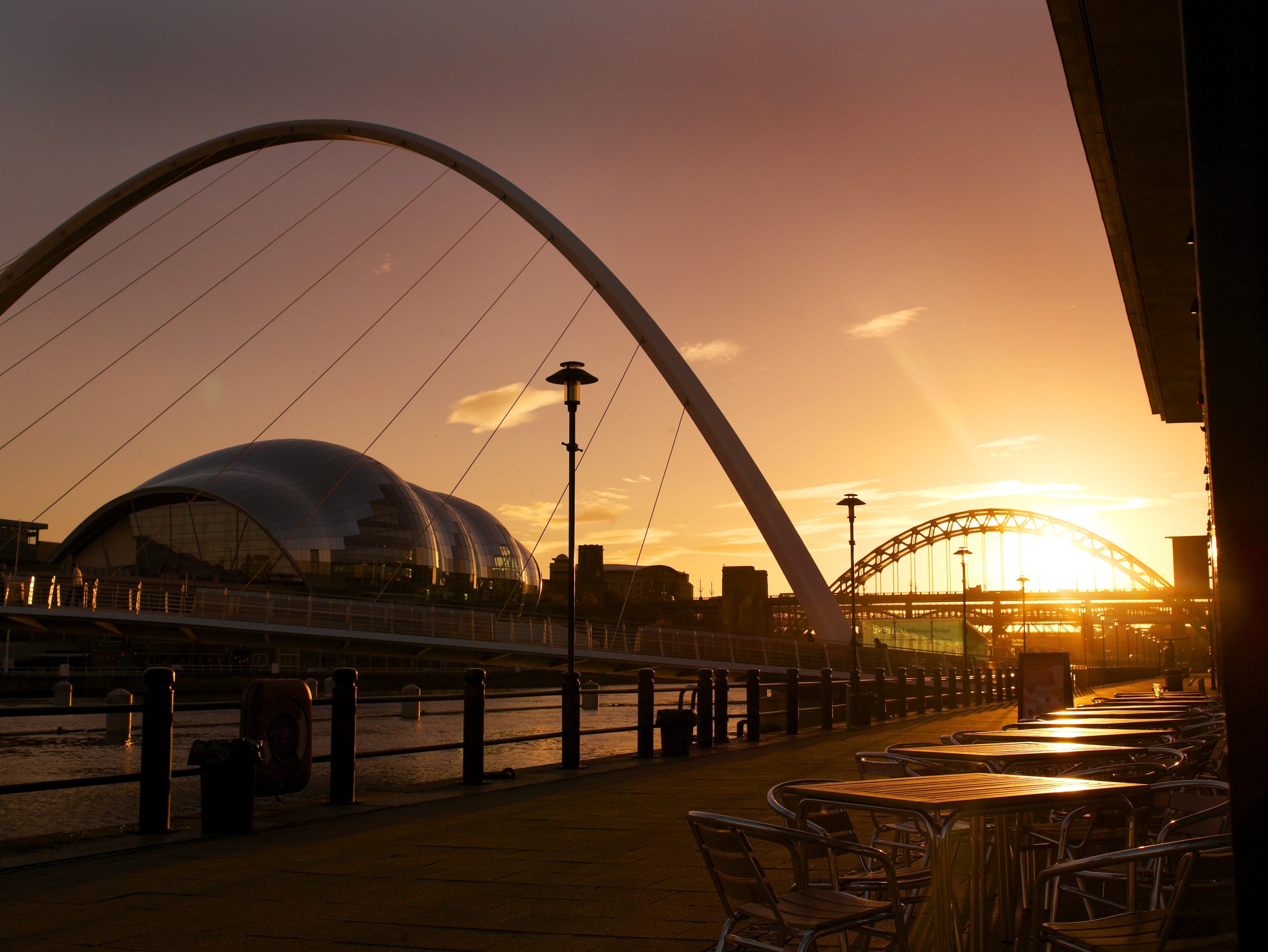 NewcastleGateshead quayside at dusk under orange sunlight.