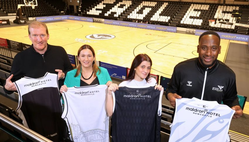 Eagles and Maldron representatives holding up the Maldron sponsored Eagles jerseys in the stands of the Eagles stadium.