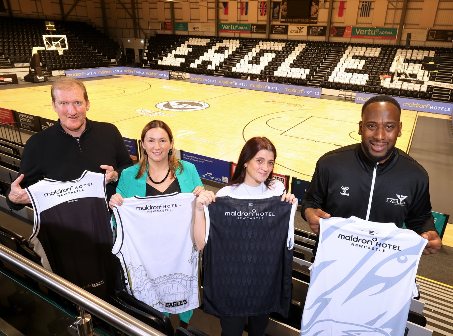 Eagles and Maldron representatives holding up the Maldron sponsored Eagles jerseys in the stands of the Eagles stadium.