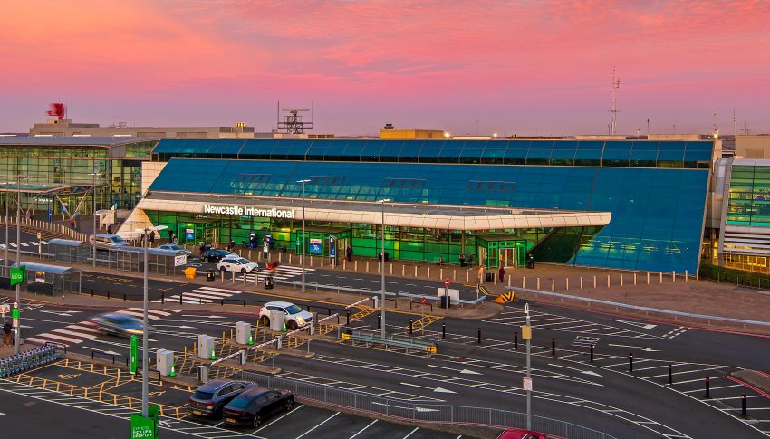 Newcastle Airport under a pink sky.