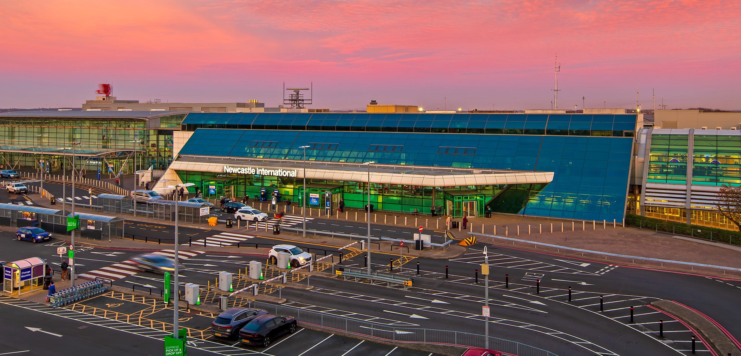 Newcastle Airport under a pink sky.