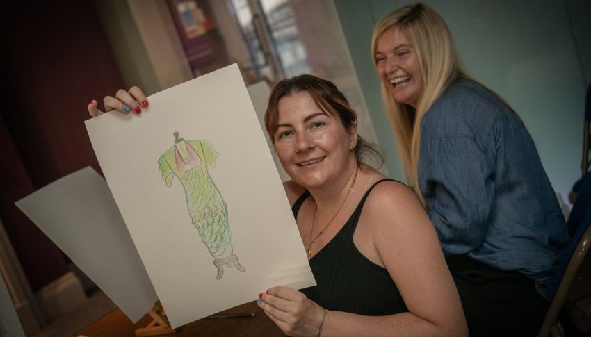 Two people holding a drawing up.