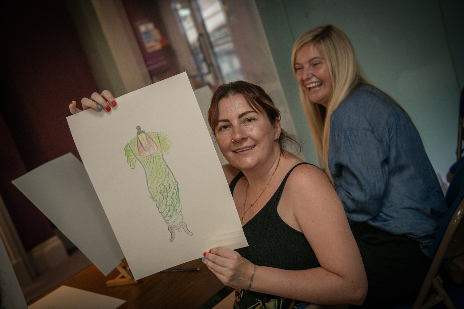 Two people holding a drawing up.