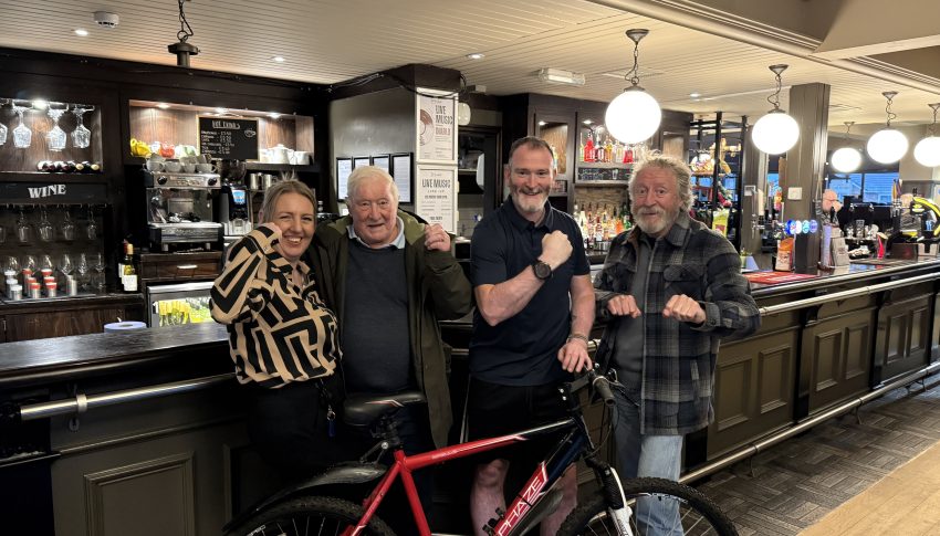 A group of people in a pub with a bike.